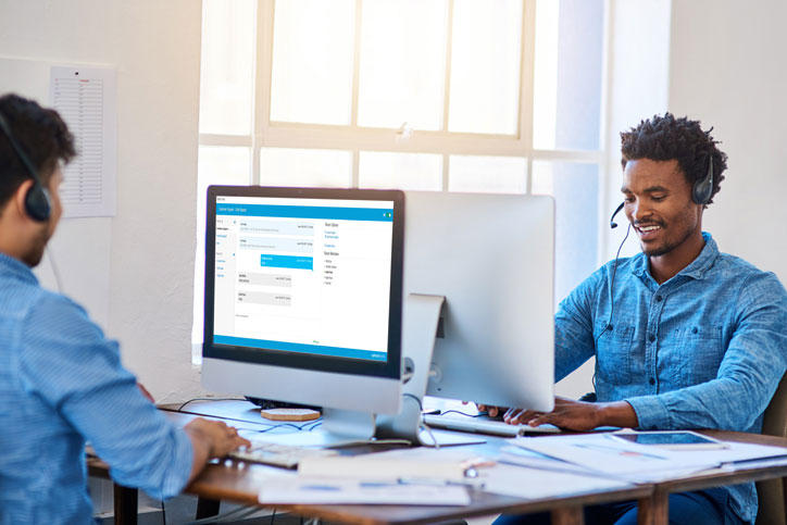 Two contact center agents on computers facing one another using chat feature